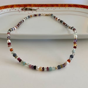 May include: A colorful beaded necklace with a variety of stones, including amethyst, aquamarine, and carnelian.