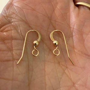May include: A pair of gold-toned earring hooks with a small ball at the top of each hook.