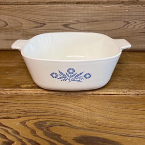 May include: White square casserole dish with a blue floral pattern. The dish has two handles and is made of a durable material. The blue floral pattern is a simple, yet elegant design.
