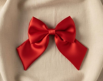 May include: A vibrant red bow crafted from a smooth, satin-like material. The bow features two symmetrical loops and two wide, angled tails extending outwards, creating a classic shape with a polished, reflective finish on the fabric surface.