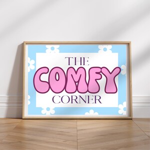 May include: A light blue and white print with a pink sign that says "The Comfy Corner".