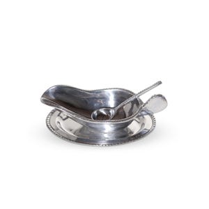 May include: Silver gravy boat with a matching ladle, both with a beaded edge. The gravy boat is on a matching plate.