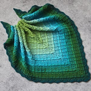 May include: A green and blue crocheted shawl with a scalloped edge.
