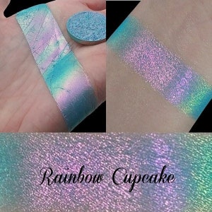 Può includere: Primo piano di un ombretto blu chiaro con un bagliore iridescente multicolore. L'ombretto è etichettato "Rainbow Cupcake".