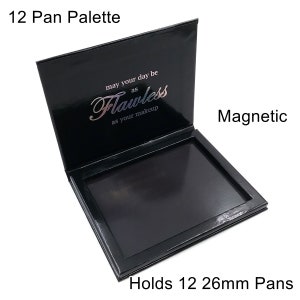 Puede incluir: Paleta de maquillaje magnética negra con tapa de espejo. La tapa tiene el texto "may your day be as flawless as your makeup". La paleta tiene capacidad para 12 pan de 26 mm.