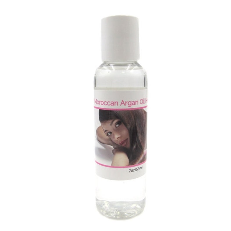 May include: A clear bottle of Moroccan Argan Oil with a white cap. The label features a woman with long brown hair. The bottle contains 2 fl oz / 59 ml of oil.
