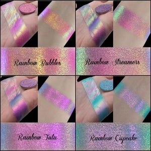 May include: A collection of iridescent eyeshadow swatches in various shades of pink, purple, blue, and green. Each swatch is accompanied by a matching eyeshadow pan. The text "Rainbow Bubbles", "Rainbow Streamers", "Rainbow Tutu", and "Rainbow Cupcake" are displayed.