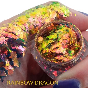 May include: A small clear jar filled with iridescent holographic flakes. The flakes are a mix of green, yellow, orange, and pink. The jar is labeled "Rainbow Dragon".