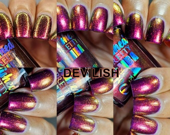 May include: A bottle of nail polish with a holographic finish. The bottle is labeled "Polished Pretty" and "Devilish". The polish is a deep purple with gold and red shimmer.