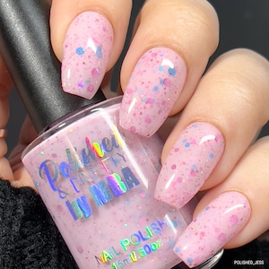 May include: Pink nail polish with a light pink base and iridescent glitter. The bottle is labeled "Polished & Pretty by MIRA" and "Nail Polish 15ml V.500z".