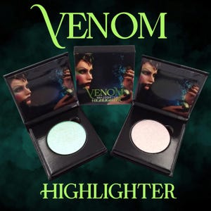 Puede incluir: Compactos de resaltador cosmético negros con la palabra "VENOM" en escritura verde arriba y "HIGHLIGHTER" abajo. Los compactos contienen un resaltador verde claro y rosa claro. Los compactos tienen una foto de una mujer en la tapa.