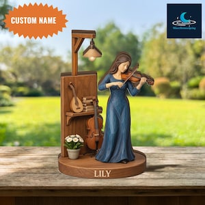 May include: A wooden figurine of a woman playing a violin, wearing a blue dress. The figurine is on a wooden base with a lamp, a small shelf with a mandolin, books, and a cello. The base has the name "LILY" and the text "CUSTOM NAME".