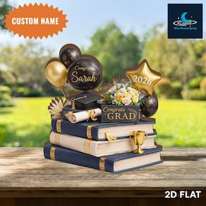May include: A graduation-themed centerpiece featuring stacked blue books, a mortarboard, a diploma, and a gold trophy. Balloons with the text "Congrats Sarah" and a star-shaped balloon with "2026" are included. A sign reads "Congrats GRAD".