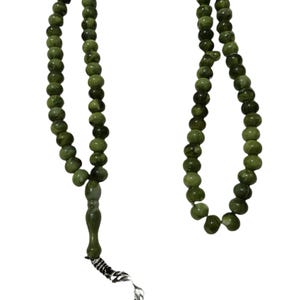 May include: A green beaded prayer rosary with a decorative tassel. The beads are a mix of light and dark green, and the tassel is made of small green beads and silver-coloured metal. The rosary is designed for prayer and meditation.