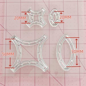 Puede incluir: Un juego de cuatro cortadores geométricos de plástico transparente con dos formas de estrella y dos formas ovaladas alargadas. Las formas pequeñas miden 20mm de altura y las grandes 50mm, según las marcas de medición en color rojo.
