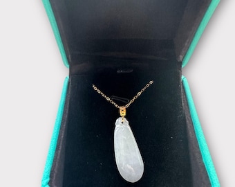 May include: A gold chain necklace with a pear-shaped, pale green jade pendant. The necklace is displayed in a teal jewelry box with a black interior. The pendant is approximately 2 inches long.