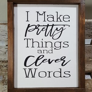 May include: A white wooden sign with a brown frame. The sign says "I Make Pretty Things and Clever Words".