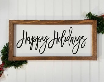 May include: A wooden framed sign with the text "Happy Holidays" in black cursive lettering on a white background.