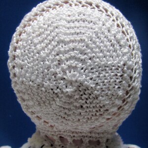 Puede incluir: Sombrero de beb&eacute; blanco de ganchillo con un delicado borde de encaje. El sombrero est&aacute; hecho con un hilo fino y tiene una textura suave y aireada.