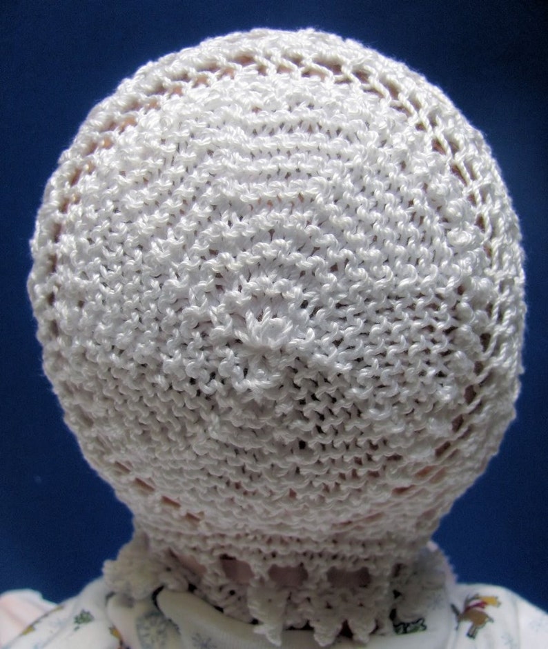 Puede incluir: Sombrero de beb&eacute; blanco de ganchillo con un delicado borde de encaje. El sombrero est&aacute; hecho con un hilo fino y tiene una textura suave y aireada.