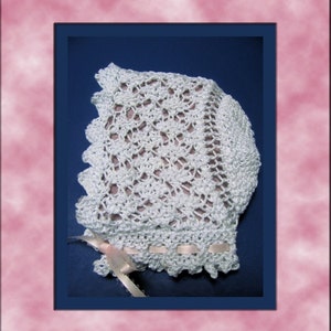 Puede incluir: Un gorro de beb&eacute; de ganchillo blanco con un delicado patr&oacute;n de encaje y una cinta de sat&eacute;n rosa atada en la parte inferior.