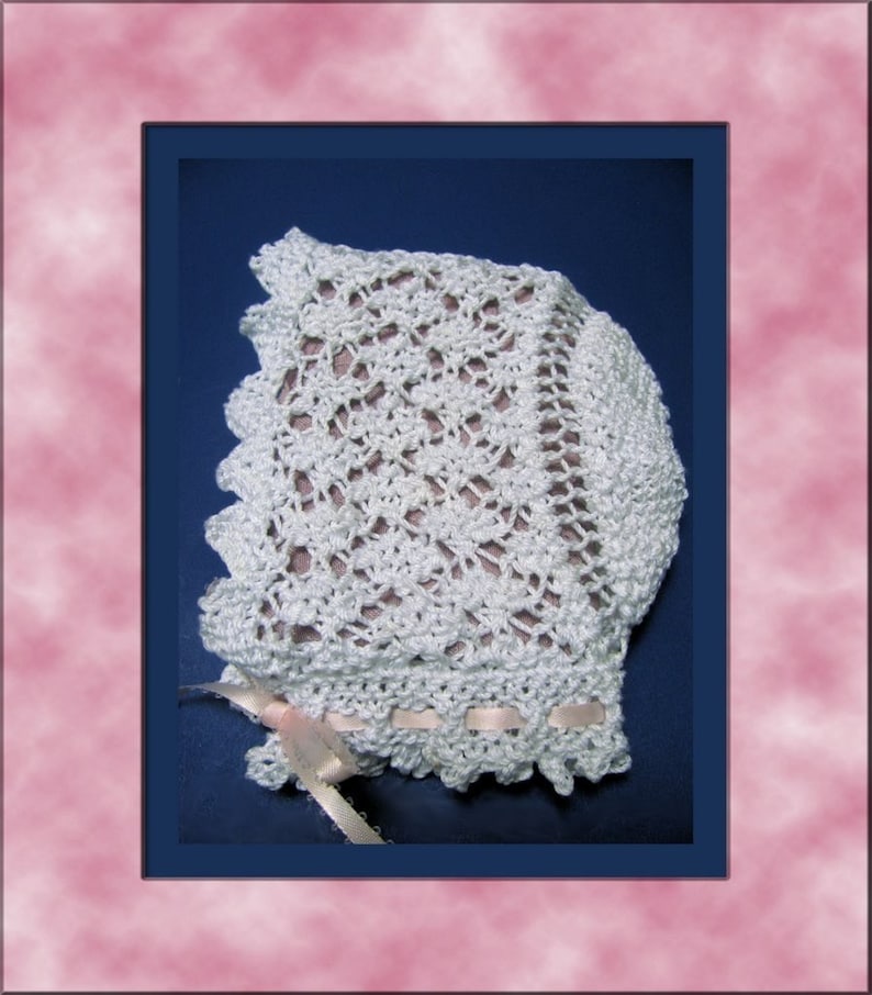 Puede incluir: Un gorro de beb&eacute; de ganchillo blanco con un delicado patr&oacute;n de encaje y una cinta de sat&eacute;n rosa atada en la parte inferior.