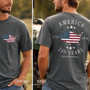 May include: Pepper-colored t-shirt with a small American flag graphic on the front and a larger flag design on the back, celebrating 250 years. The shirt includes the text "AMERICA 1776-2026 250 YEARS SEMIQUINCENTENNIAL".
