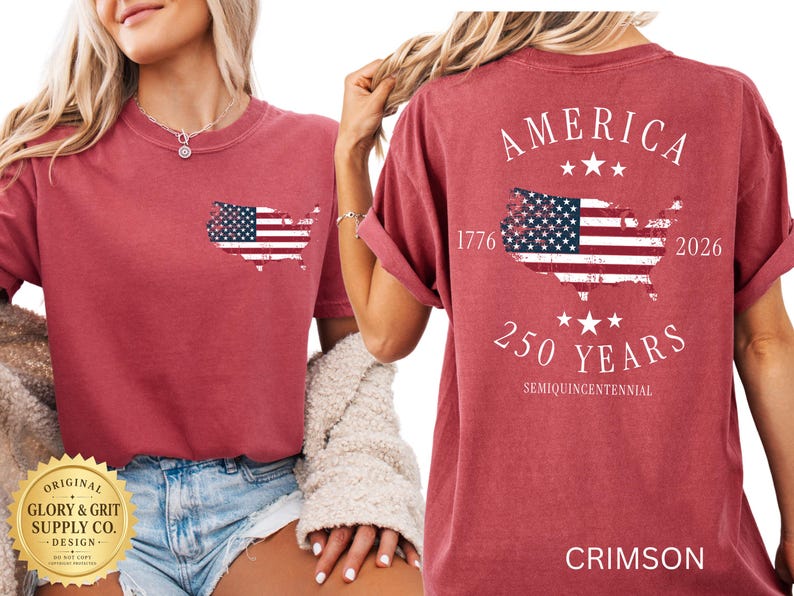 May include: Crimson-colored t-shirt featuring an American flag design. The front has a small flag outline, while the back displays "AMERICA" above a flag map, "1776-2026", and "250 YEARS". The shirt is a comfortable, casual style.