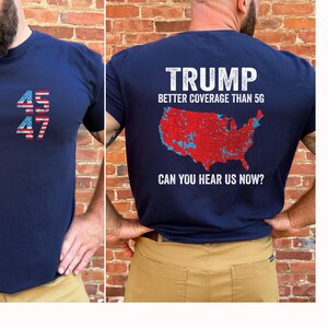 May include: A navy blue t-shirt with a red, white, and blue American flag design on the front and a map of the United States with the text "TRUMP BETTER COVERAGE THAN 5G CAN YOU HEAR US NOW?" on the back.
