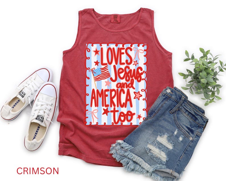 K&ouml;nnte beinhalten: Karmesinrotes Tanktop mit dem Text "Loves Jesus and America too" in Rot und Wei&szlig;. Das Tanktop wird mit Jeansshorts und wei&szlig;en Turnschuhen kombiniert. Das Design beinhaltet eine amerikanische Flagge und Sterne.