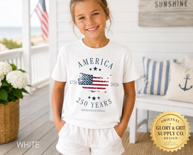May include: A white t-shirt with the word "AMERICA" above a graphic of the American flag within a map of the United States. The text "1776" and "2026" flank the flag, with "250 YEARS" below. The shirt is worn by a young person.