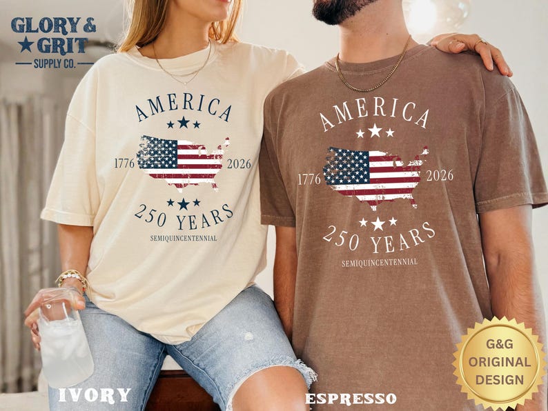 May include: Two t-shirts, one ivory and one espresso, each with a graphic celebrating America's 250th anniversary. The design includes the word "AMERICA", a map of the USA with the American flag, and the years 1776 and 2026.