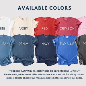 May include: A display of t-shirts in various colors, including white, ivory, red, crimson, blossom, blue jean, denim, navy, flo blue, and pepper. Each shirt has a crew neck and short sleeves. The text "AVAILABLE COLORS" is at the top.