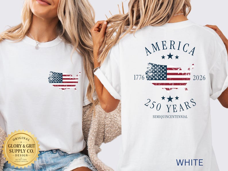 May include: White t-shirt featuring a distressed American flag design in the shape of the United States. The back of the shirt displays "AMERICA" above a flag graphic, with "1776" and "2026" flanking the flag, and "250 YEARS" below.