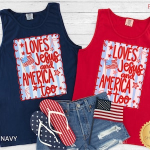 K&ouml;nnte beinhalten: Zwei Tanktops, eines in Marineblau und eines in Rot, mit dem Text "Loves Jesus and America too" und einer amerikanischen Flagge. Das Bild zeigt auch Jeansshorts und Flip-Flops.