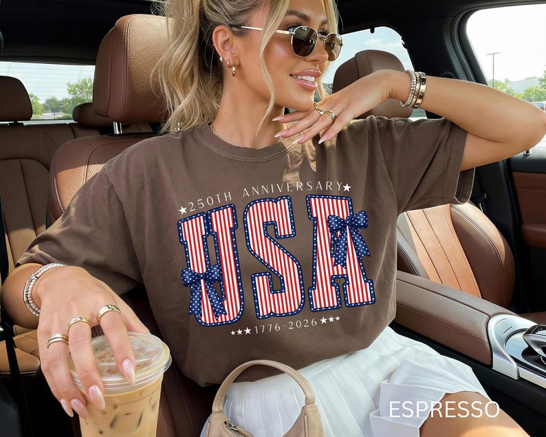 May include: A brown t-shirt with the text "USA" in red and white stripes, with blue bow accents. The shirt also features the text "250TH ANNIVERSARY" and "1776-2026". The word "ESPRESSO" is at the bottom of the image.