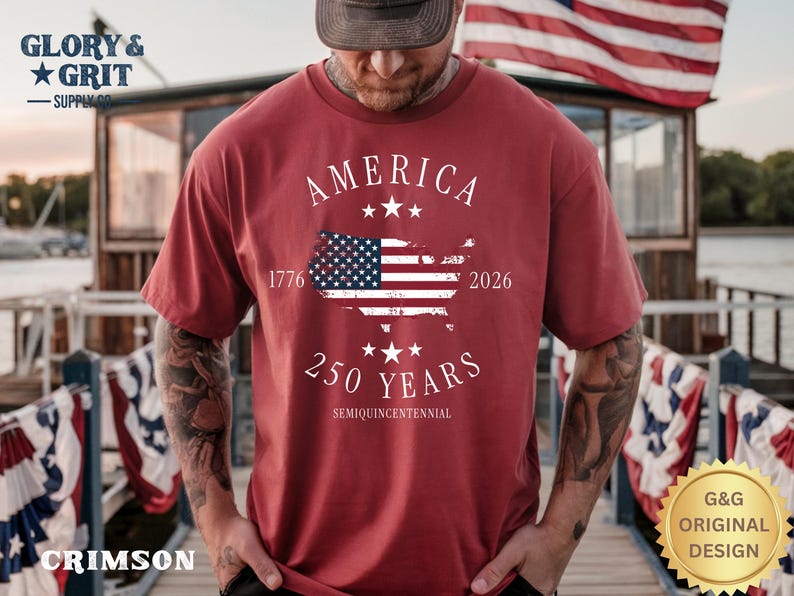 May include: Crimson t-shirt with the text "AMERICA" and a map of the United States with the American flag. The shirt also features the text "1776 2026 250 YEARS SEMIQUINCENTENNIAL". The shirt has a "G&G ORIGINAL DESIGN" logo.