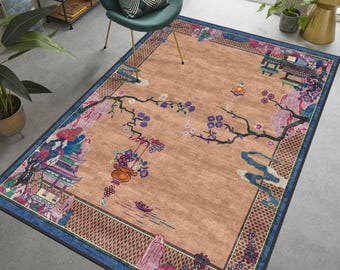 May include: A beige area rug with a blue border and a floral design. The rug features a large tree with pink and purple flowers, a pagoda, and a hanging basket of flowers. The rug has a detailed border with a geometric pattern.