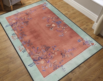 May include: A vintage-style rug with a floral design in shades of pink, blue, and green. The rug has a light blue border and a dark brown background.