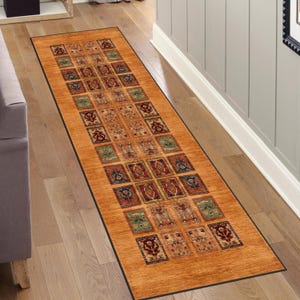 May include: A long runner rug with a geometric pattern in shades of brown, red, blue, and green. The rug has a black border and is laid out on a wooden floor.