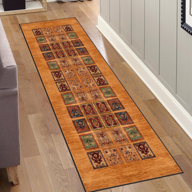 May include: A long runner rug with a geometric pattern in shades of brown, red, blue, and green. The rug has a black border and is laid out on a wooden floor.