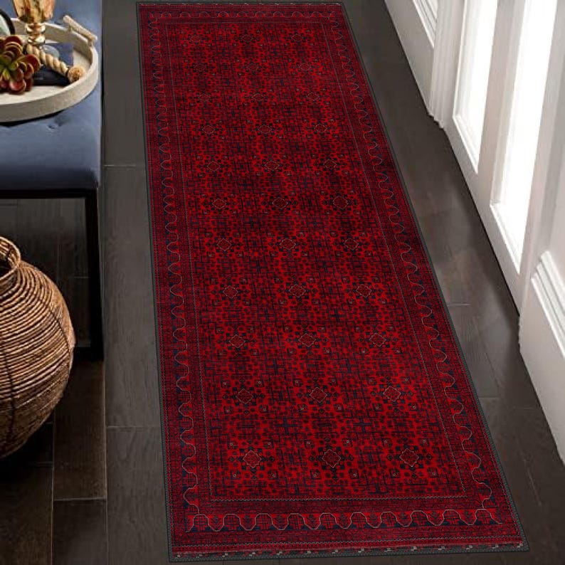 May include: A red runner rug with a black and white geometric pattern. The rug has a border with a wavy design.