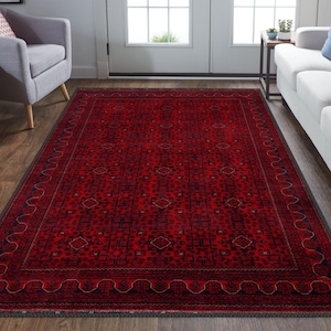 May include: A red and black area rug with a traditional Persian design. The rug has a dark border with a repeating pattern of small diamonds and a central field with a geometric pattern.