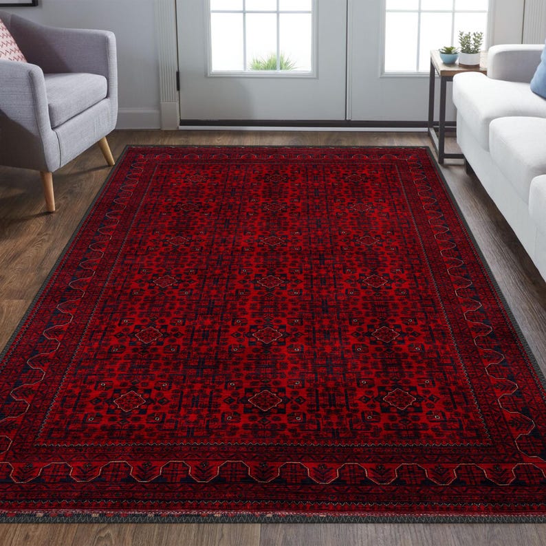 May include: A red and black area rug with a traditional Persian design. The rug has a dark border with a repeating pattern of small diamonds and a central field with a geometric pattern.
