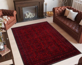 May include: A red and black patterned rug with a dark border. The rug is laid out on a wooden floor in a living room setting.
