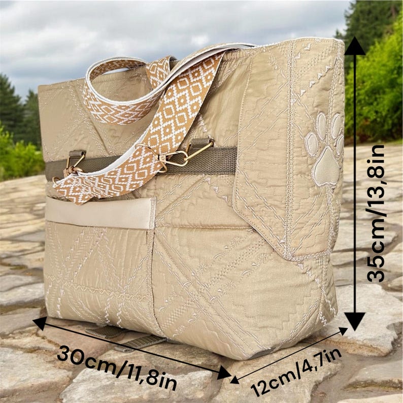 May include: Beige quilted tote bag with a patterned shoulder strap and a paw print design. The bag measures 30cm/11.8in long, 35cm/13.8in high, and 12cm/4.7in wide. Features a front pocket and gold-colored hardware.