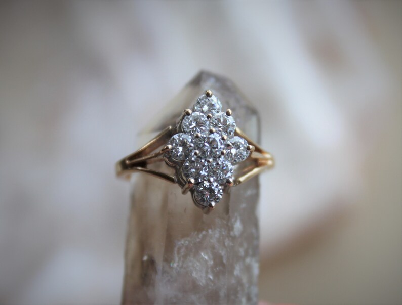 May include: A gold ring with a large cluster of clear diamonds set in a flower-like design.