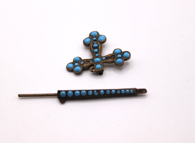 May include: An antique bronze cross pendant and matching pin, both decorated with turquoise-coloured stones. The cross has a detailed design, while the pin has a row of stones. A vintage jewellery set.