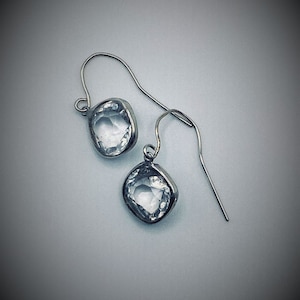 May include: A pair of silver earrings with clear faceted crystal stones.