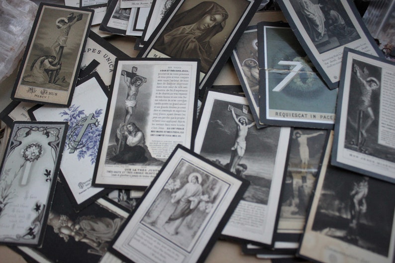 May include: A collection of vintage religious cards with black and white images of Jesus Christ on the cross, Mary, and other religious figures. The cards have a distressed look and are printed on thick paper.